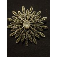 Винтажная брошь-цветок в форме ромашки или хризантемы с темными кристаллами имитирующими марказиты, и крупным светлым кристаллом в центре.