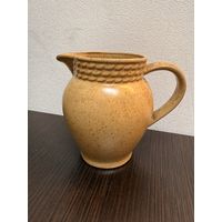 Керамический кувшин, выполненный в тёплых бежево-коричневых тонах с крапчатой текстурой.
